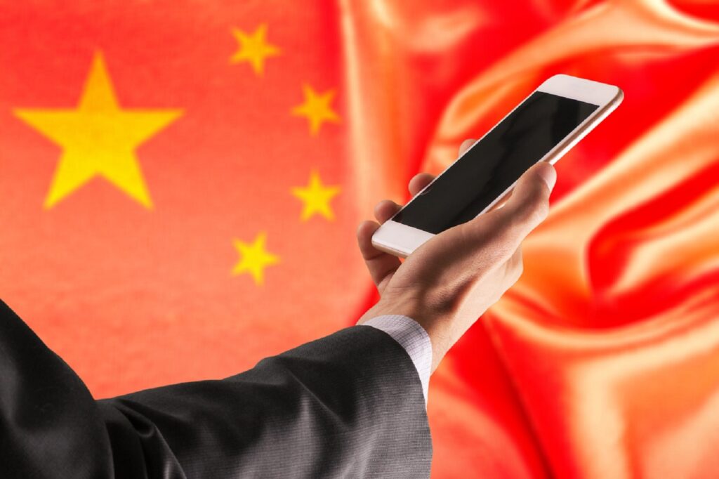 中国国旗の前でスマホを持っている男性