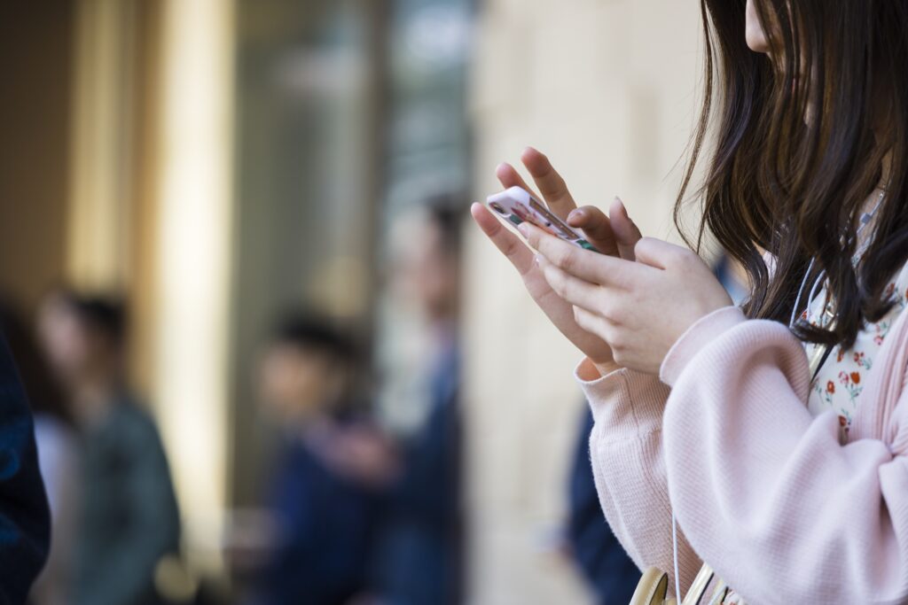 ピンクの服を着た女性がスマホを操作している