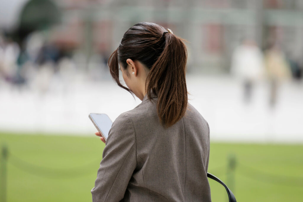 スマートフォンを見る女性が公園で佇んでいる