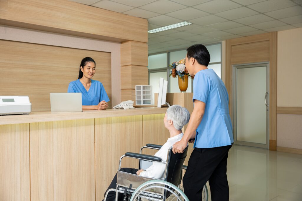 車いすを押す男性と受付の女性