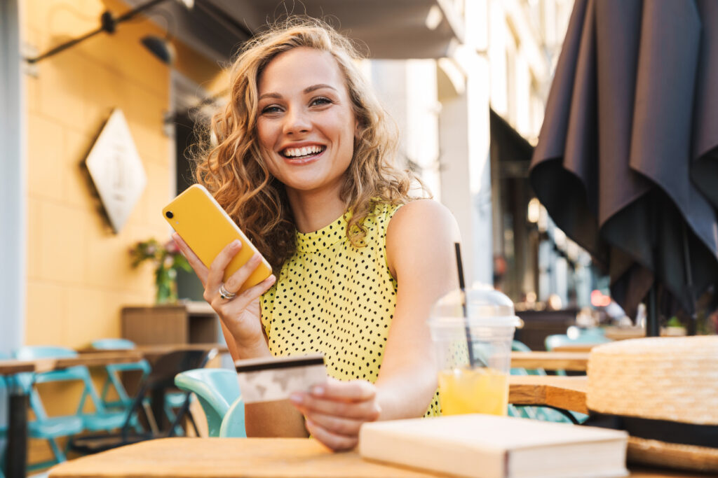 飲食店でジュースを飲みながらスマートフォンを持っている女性